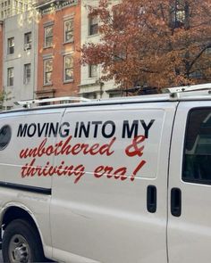 a moving van parked on the side of the road in front of some tall buildings