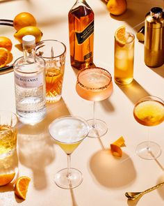 several different types of alcoholic drinks on a table with oranges and lemons in the background