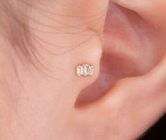 a woman's ear with three small diamond studs