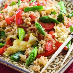 a plate with rice, vegetables and chopsticks on it