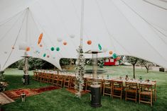 a large tent with tables and chairs set up for an outdoor wedding reception in the grass