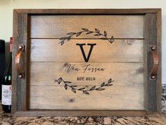 a wooden sign with the letter v on it next to a bottle of wine and a corkscrew