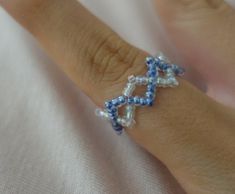 a close up of a person's hand wearing a ring with beads on it