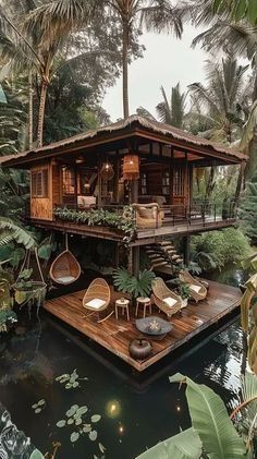 the house is surrounded by greenery and palm trees, with chairs on the deck