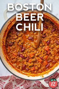 a large pot filled with chili next to a wooden spoon