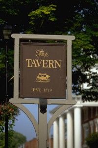 a sign for the tavern in front of some trees