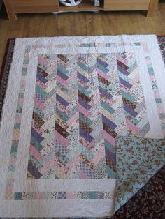 two quilts are laying on the floor next to a coffee table with a clock