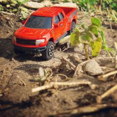 a red toy truck is parked in the dirt