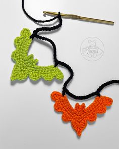 two crocheted necklaces with an orange and green bird hanging from it's side