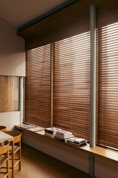 there is a table and chairs in front of the window with wooden blinds on it