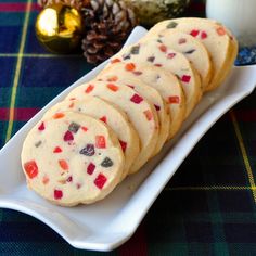 cookies are arranged on a white plate next to a glass of milk and pine cones