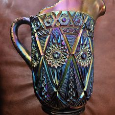 an ornate glass pitcher sitting on top of a brown leather couch next to a wall