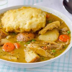 a bowl of chicken pot pie soup with biscuits and carrots on the side is ready to be eaten