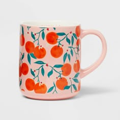 a pink mug with oranges and leaves on the inside is sitting in front of a white background