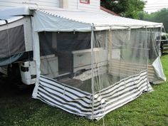 a tent that is sitting in the grass next to a house with a television on it