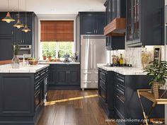 a kitchen with dark blue cabinets and wood flooring is pictured in this image, there are lights hanging from the ceiling