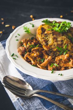 a white plate topped with meat covered in sauce and garnished with parsley