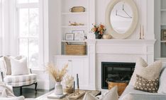 a living room filled with furniture and a fire place in front of a mirror on the wall