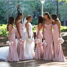 a group of women standing next to each other in long pink dresses and holding bouquets