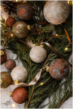 some ornaments are laying on the floor next to christmas tree branches with lights and ribbons