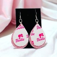 pair of pink and white earrings on display in black box with pink fabric behind it