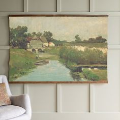 a painting hanging on the wall next to a chair in front of a white paneled wall