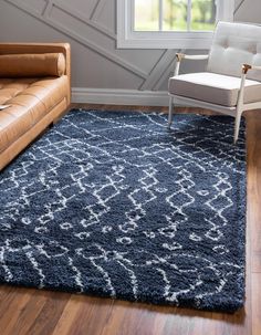 a living room area with a couch, chair and rug on the floor in front of a window