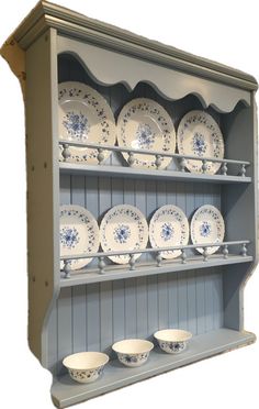 an old china cabinet with blue and white dishes on it's shelves, against a white background