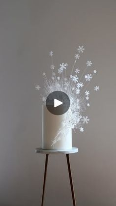 a white cake sitting on top of a table next to a wooden stand with snow flakes