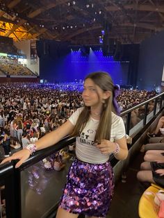 a woman standing on top of a railing in front of an audience at a concert