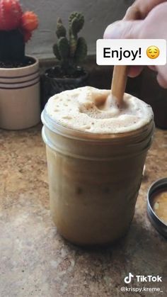 a person is holding a wooden spoon in a jar