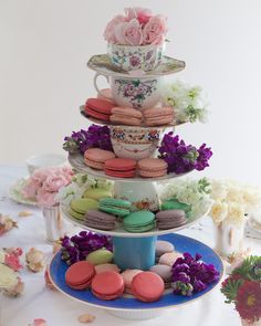 a three tiered cake stand filled with macaroons and flowers