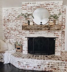 a living room with a brick fireplace and mirror on the mantel above it's mantle