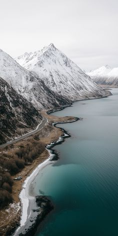 an aerial view of snow covered mountains surrounding a body of water in the middle of nowhere