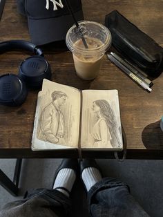 an open book sitting on top of a wooden table next to a cup of coffee