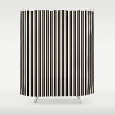 a black and white shower curtain with vertical lines on the side, in front of a gray background