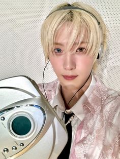 a young man wearing headphones and holding a large object in front of his face