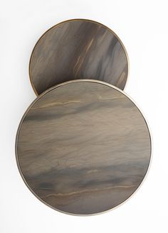 two round wooden trays sitting next to each other on top of a white surface