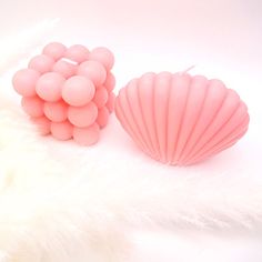 two pink seashells sitting next to each other on a white fur covered surface