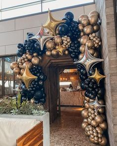 an entrance to a building decorated with balloons and gold stars in the shape of starbursts