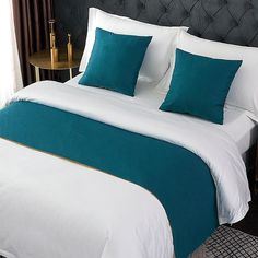 a bed with blue and white pillows on top of it next to a night stand