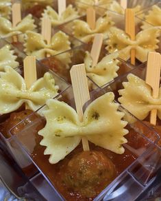 small trays filled with pasta and meatballs on sticks, ready to be eaten