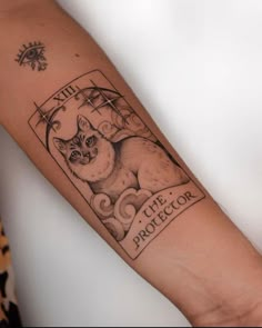 a black and white photo of a cat tattoo on the left arm, with an image of a cat behind it