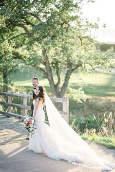 a bride and groom standing on a bridge