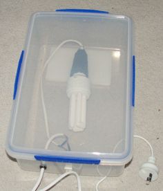 an electronic device in a plastic case on the floor with wires and plugs attached to it