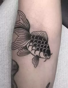 a black and white fish tattoo on the arm