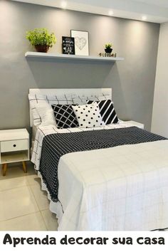 a white bed with black and white pillows on it's headboard in a bedroom