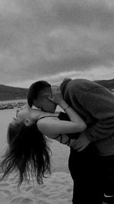 a man and woman kissing on the beach