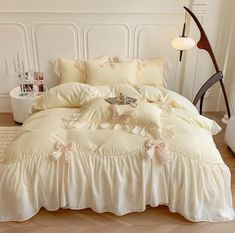 a white bed with ruffled bedspread and pillows on the floor in a room