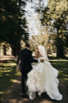 a bride and groom walking down a path